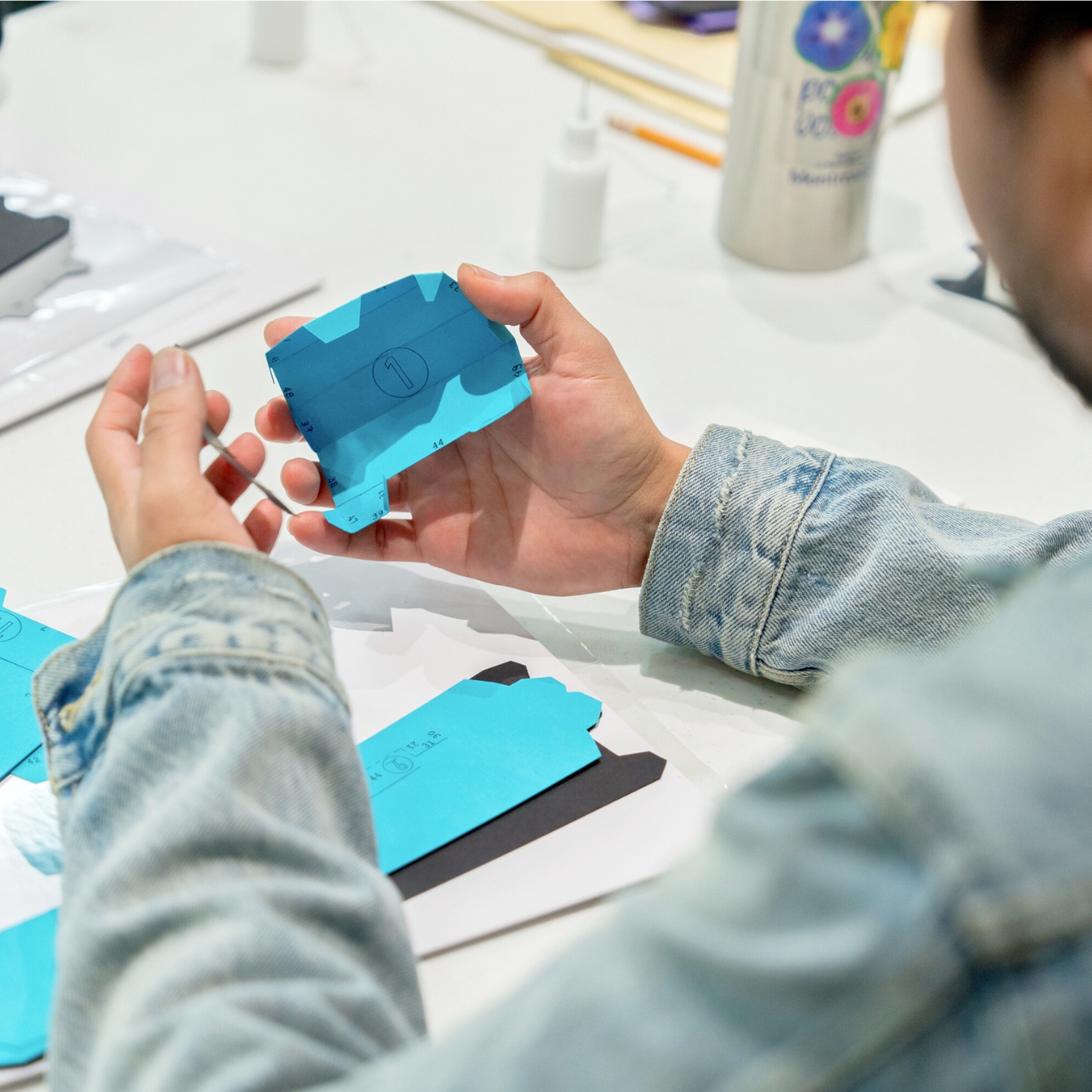 Mains assemblant une création en papier bleu